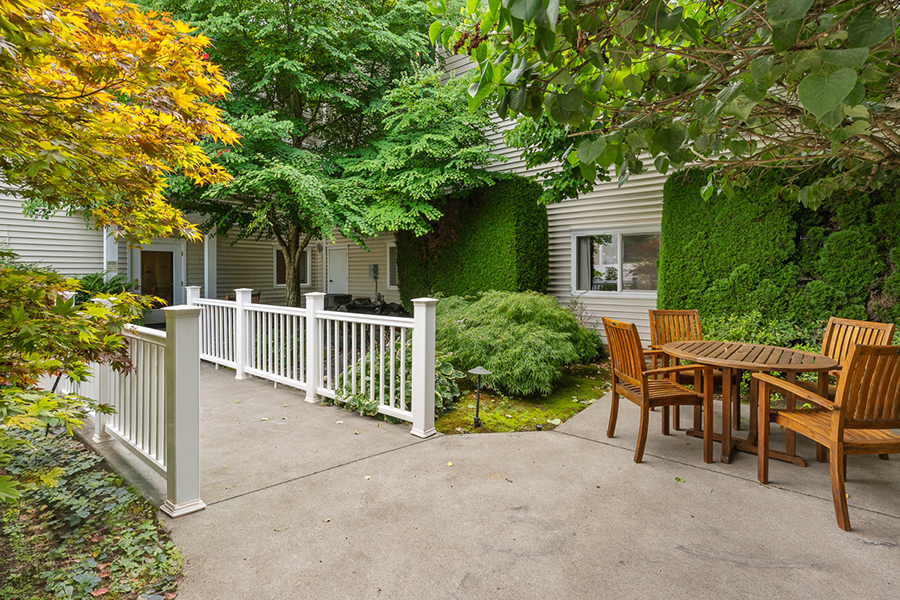 Lush garden patio with wooden furniture and greenery.