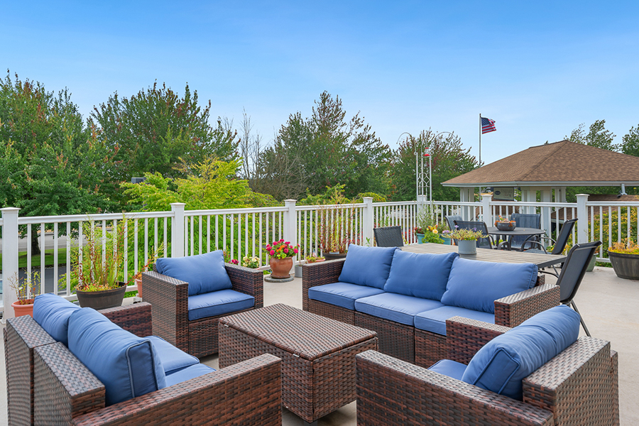 Cozy patio with blue furniture and lush greenery.