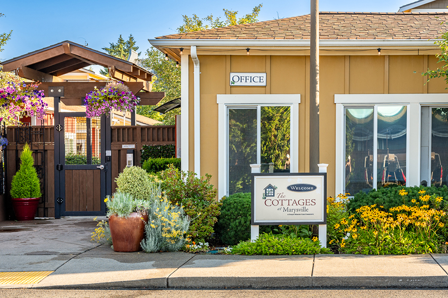 Cottages entrance with colorful flowers and welcoming sign.