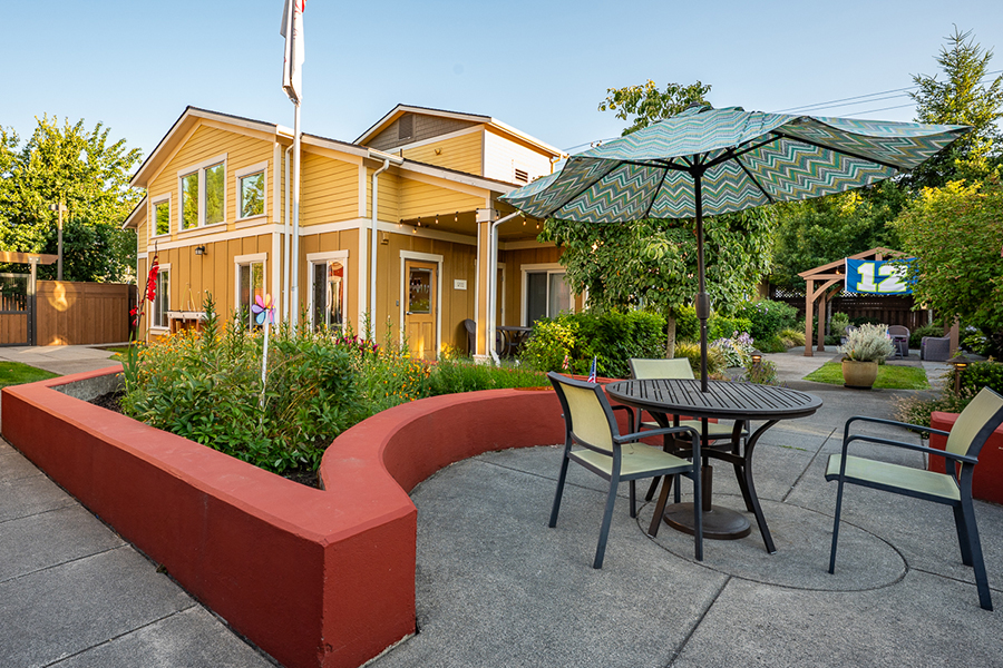 Cozy yellow house with patio and garden seating area.