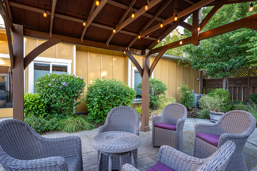 Cozy outdoor seating area with plants and string lights.