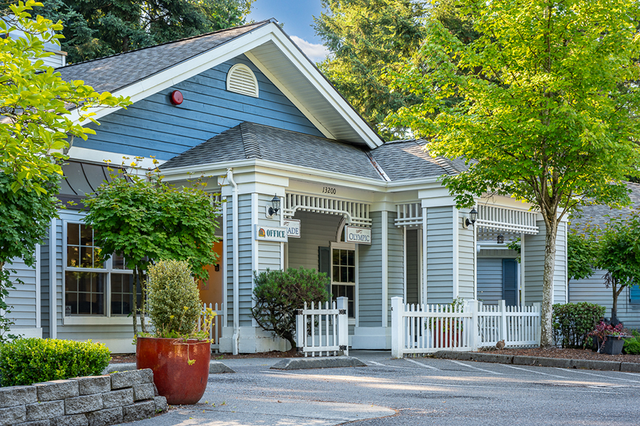 Charming blue building with green surroundings and white fence.