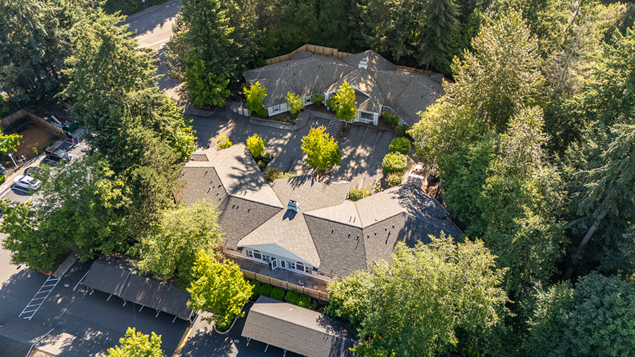 Aerial view of a house surrounded by trees and parking.