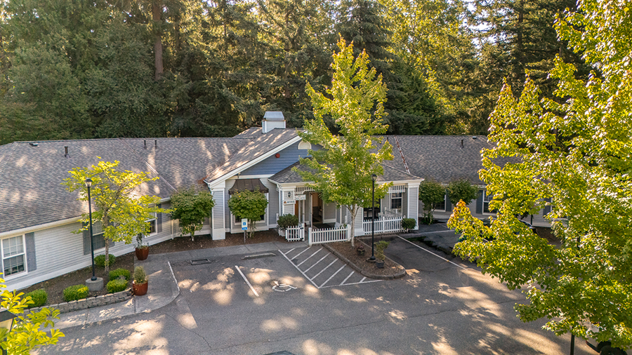 Spacious building surrounded by trees and parking area.