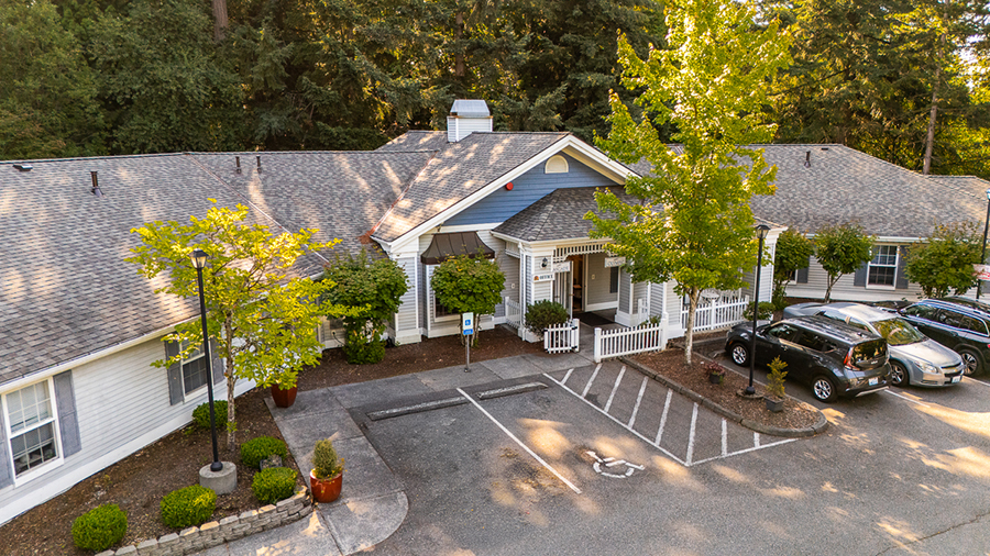 Building entrance surrounded by trees and parking spaces.