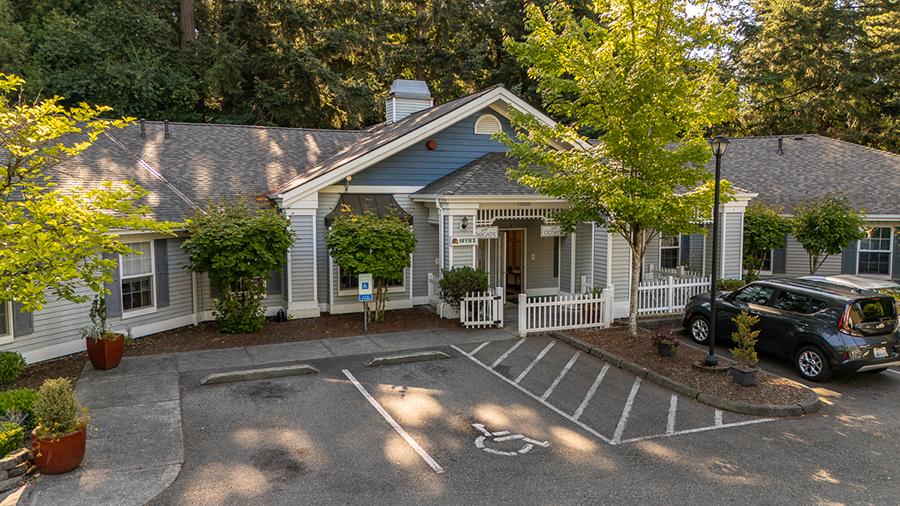 Peaceful building with trees and parking area in front.