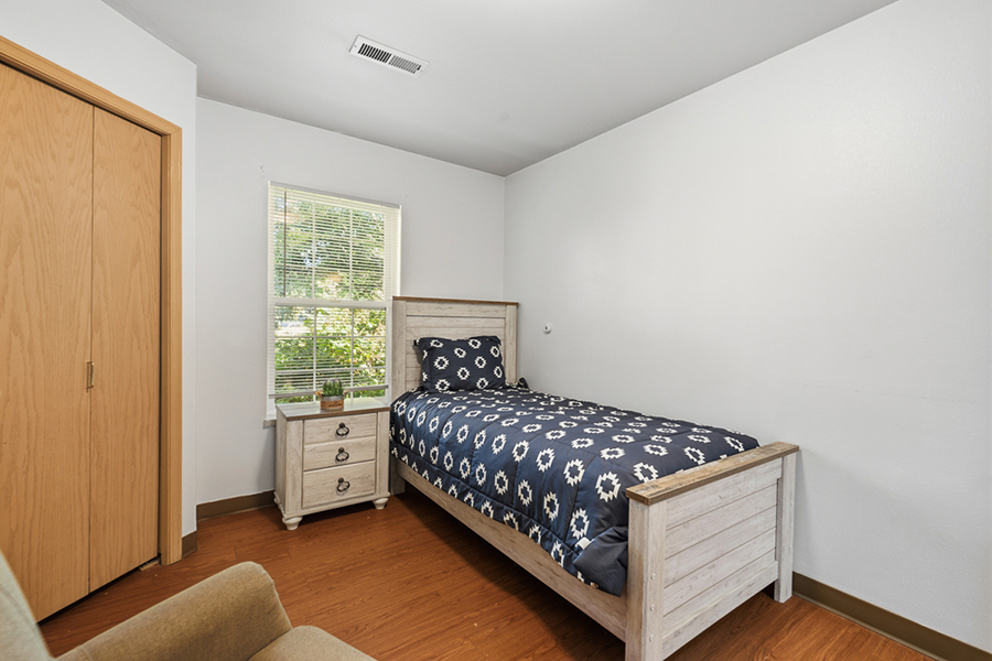 Cozy bedroom with a bed, window, and wooden furniture.