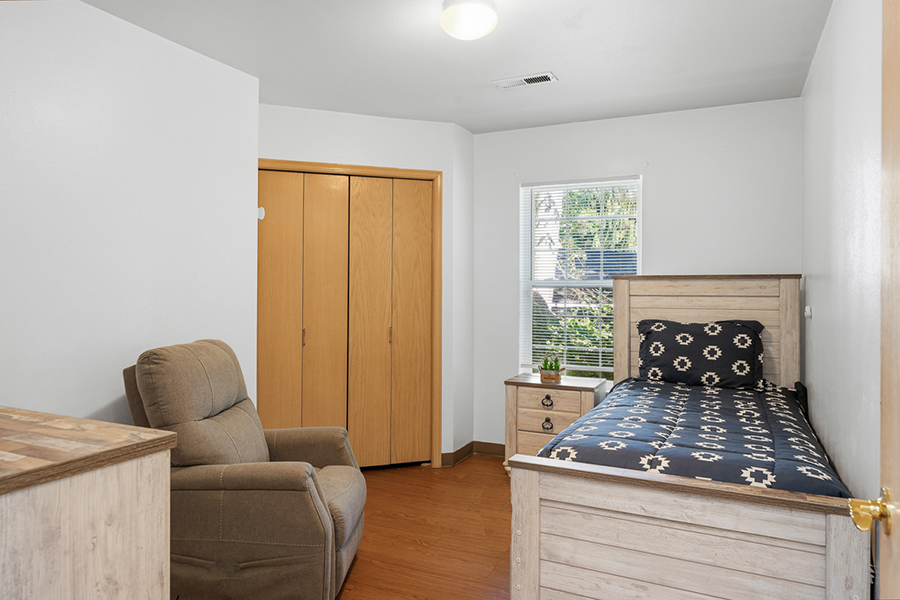Cozy bedroom with bed, recliner, and closet space.