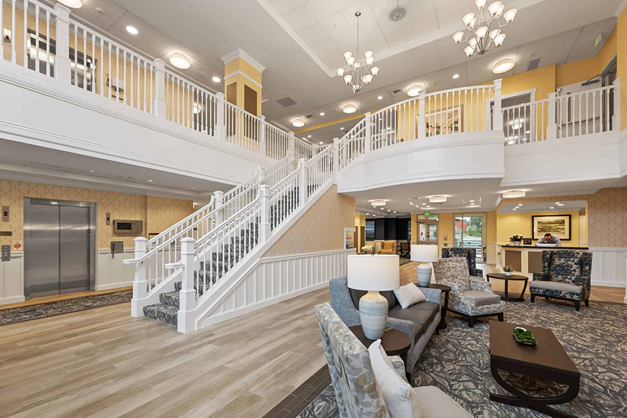 Spacious, elegant lobby with stairs, seating, and elevators.