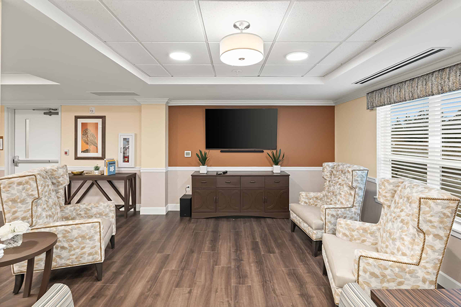 Cozy lounge with chairs, television, and natural light.