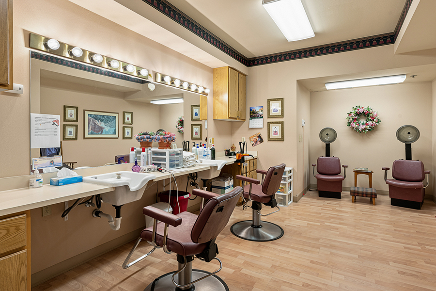 Hair salon with chairs, mirror, and styling products.