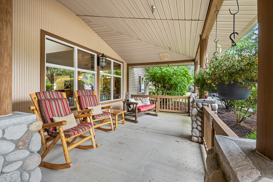 Cozy porch with rocking chairs and lush greenery.