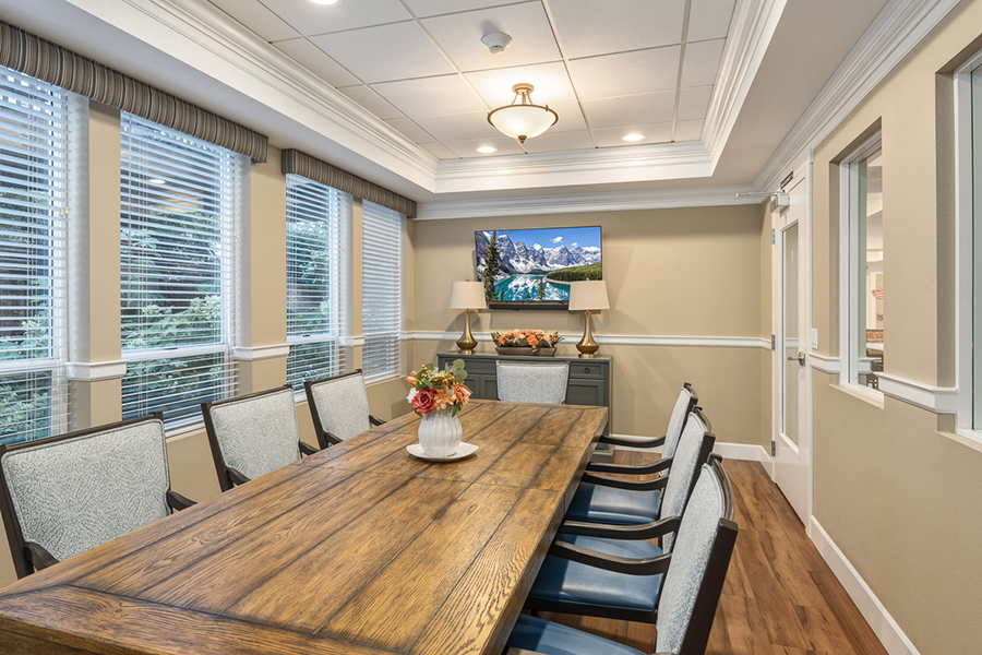 Modern meeting room with wooden table and large windows.