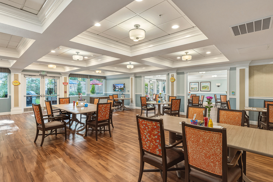 Bright dining area with wooden floors and colorful chairs.