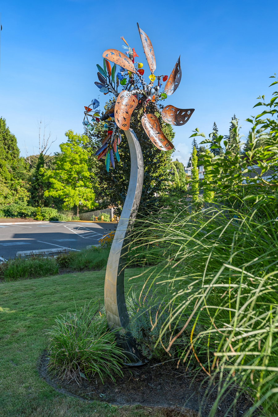 Colorful metal sculpture resembling a flower in a garden.