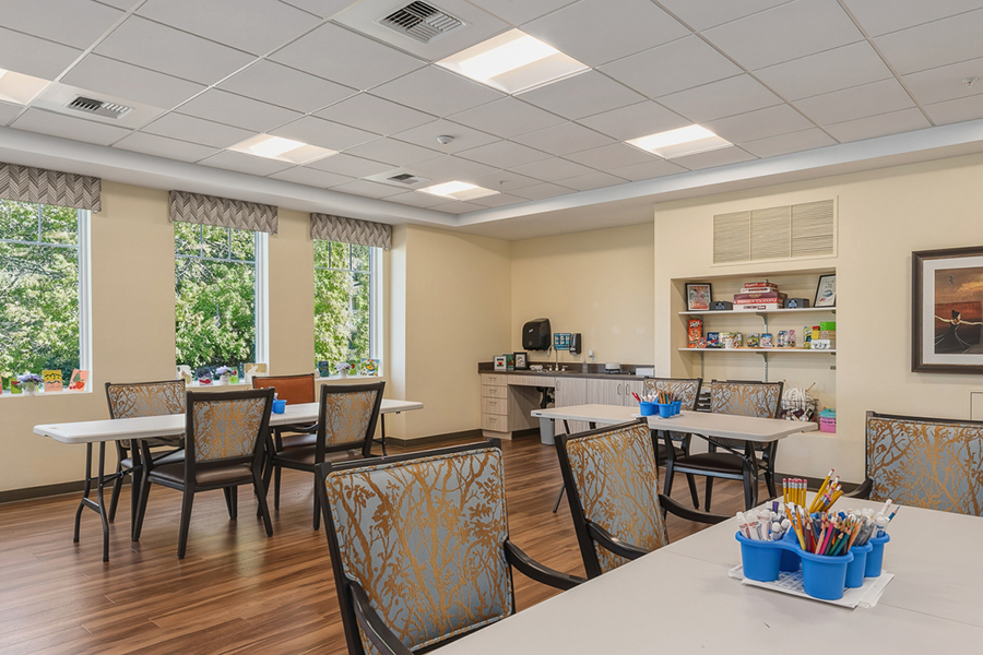 Bright activity room with tables, chairs, and art supplies.
