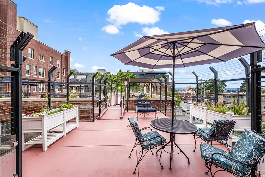 Rooftop terrace with seating, plants, and an umbrella.