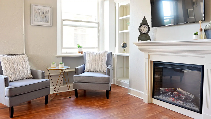 Cozy living room with chairs, fireplace, and plants.