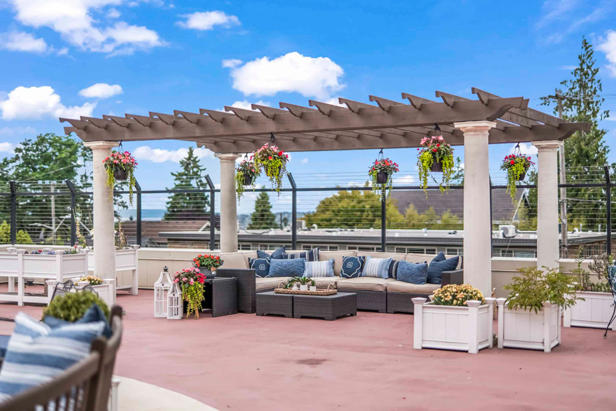 Rooftop seating area with pergola and colorful plants.