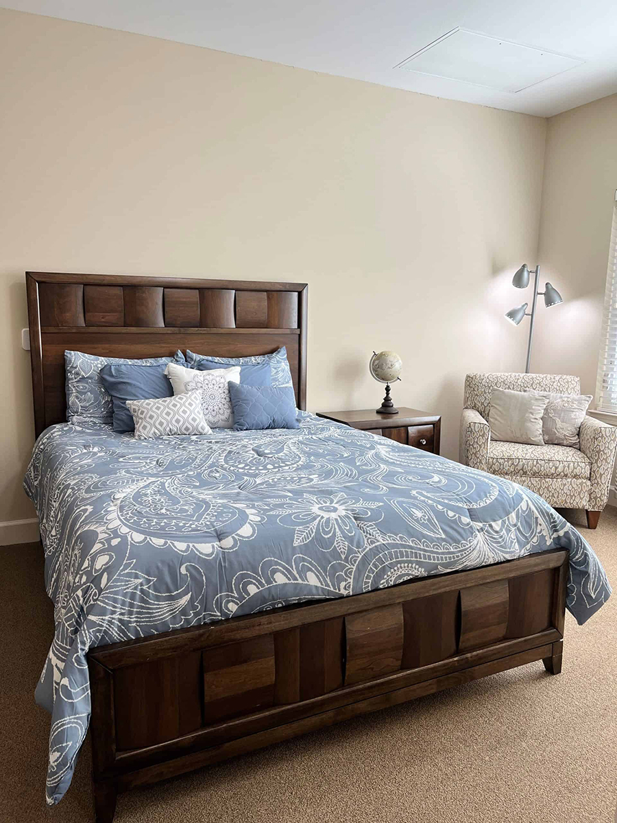 Cozy bedroom with a blue patterned bedspread and armchair.