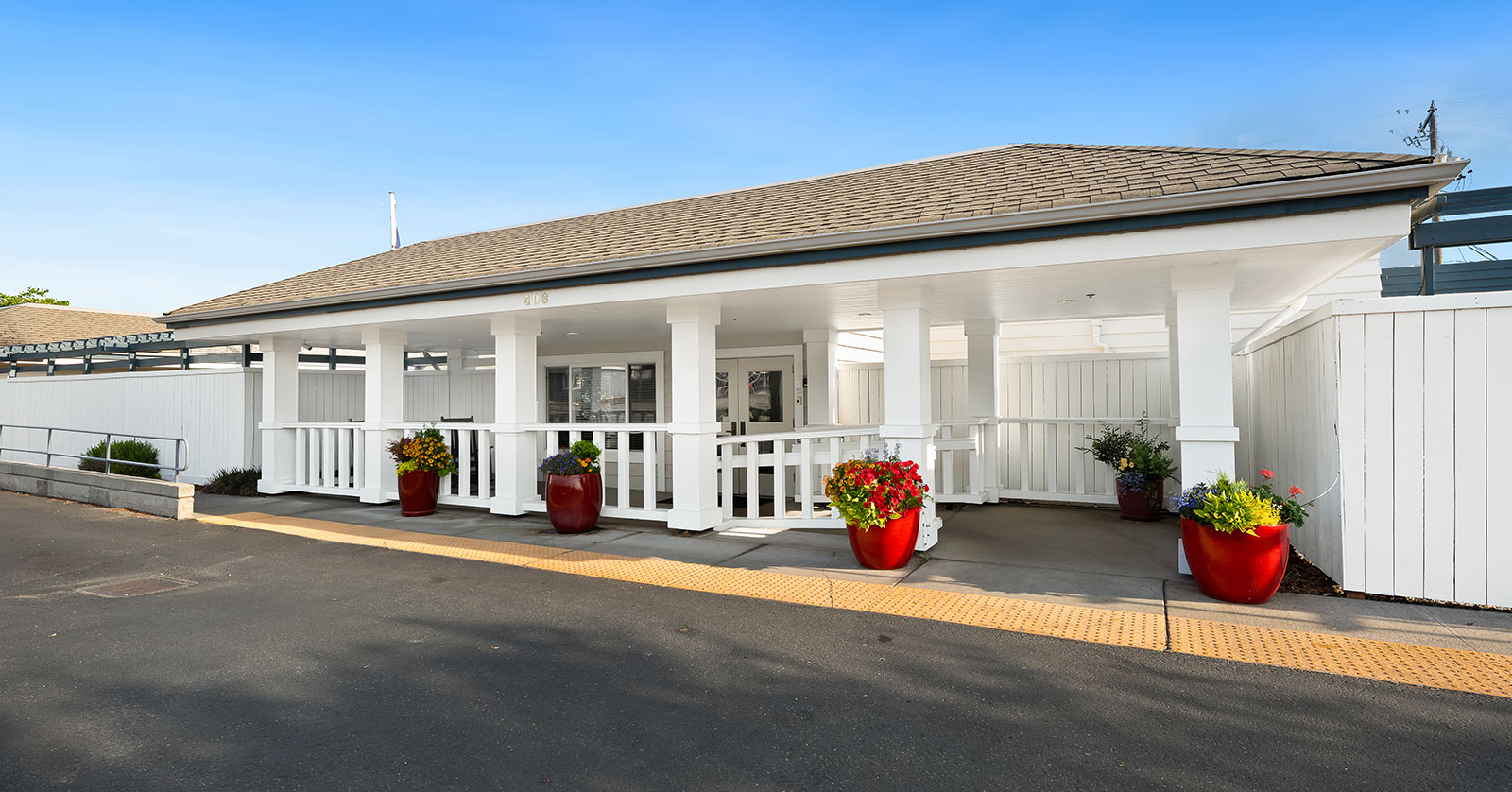 White building entrance with flower pots and clear sky.