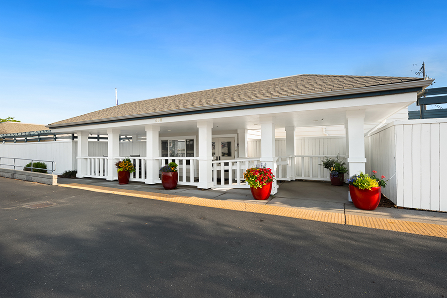 White building entrance with flower pots and clear sky.