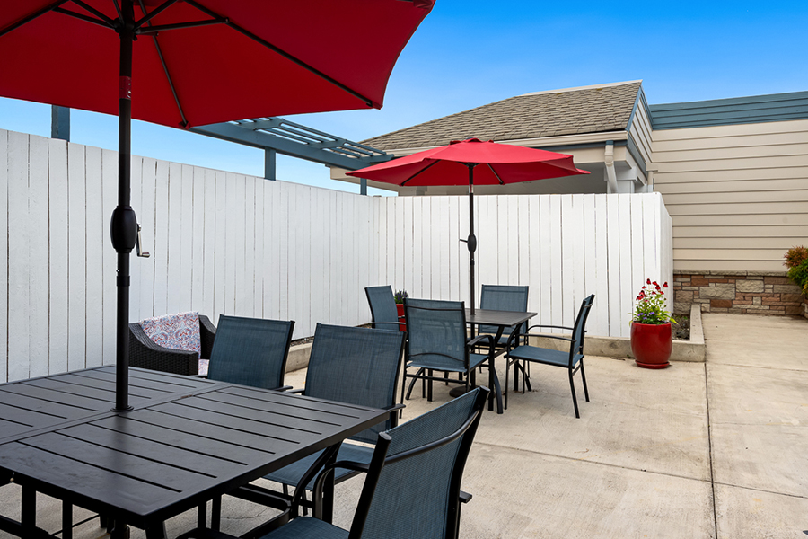 Outdoor dining area with red umbrellas and black furniture.