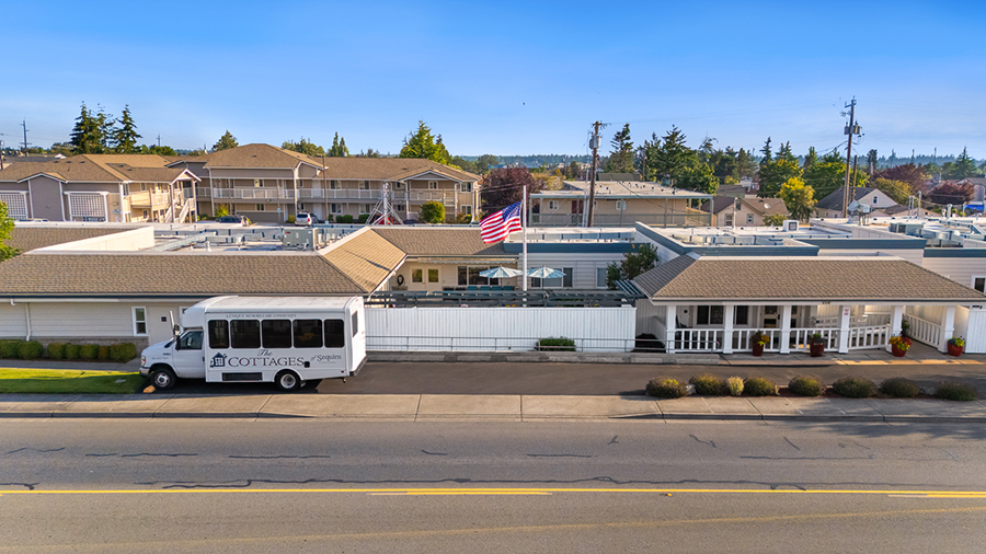 Residential area with a white shuttle bus and American flag.