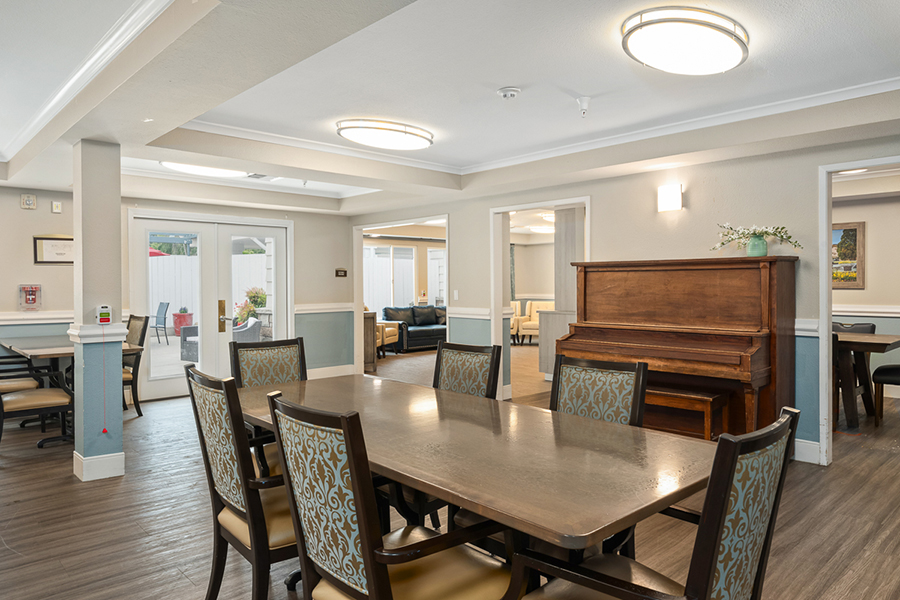 Cozy communal space with dining table and piano.