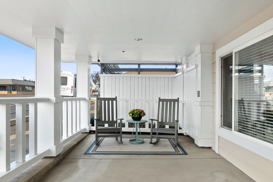 Covered porch with rocking chairs and a table.