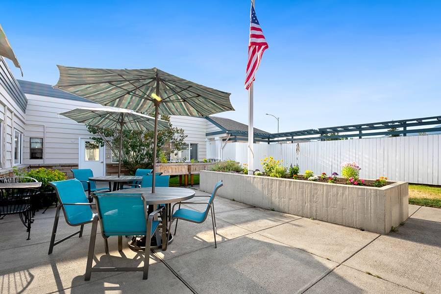 Patio with umbrellas, seating, flowers, and American flag.