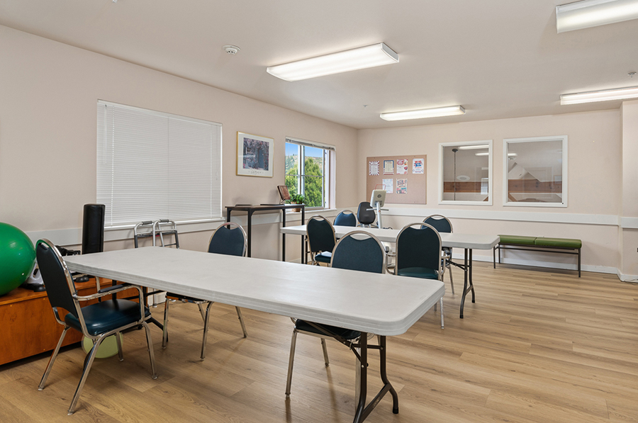 Bright, spacious room with tables, chairs, and windows.
