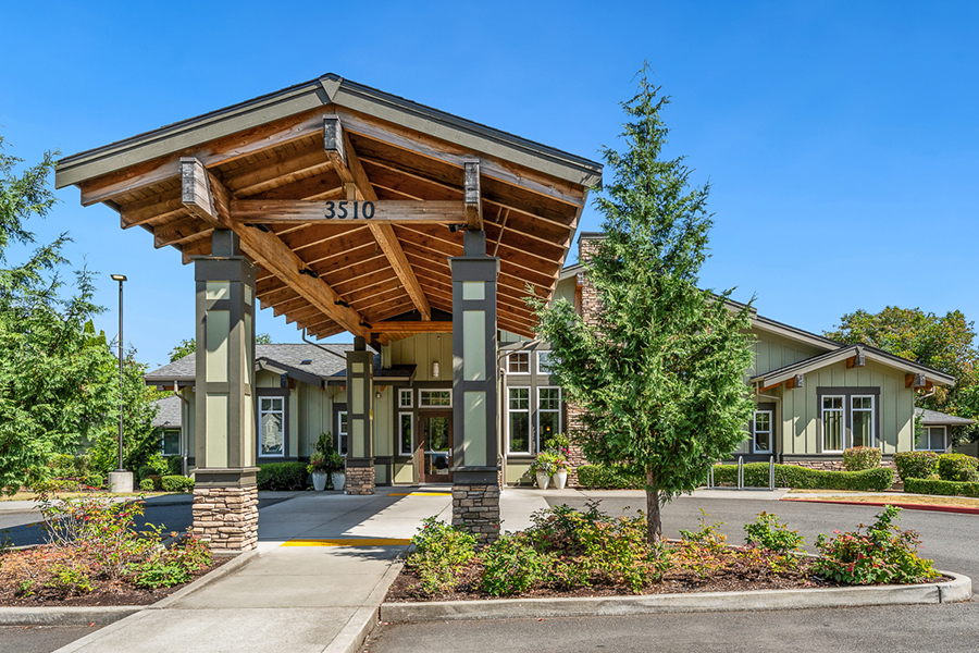 Modern building entrance with trees and clear blue sky.