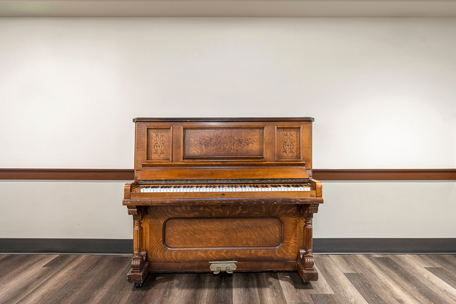 Antique wooden piano against a plain wall.
