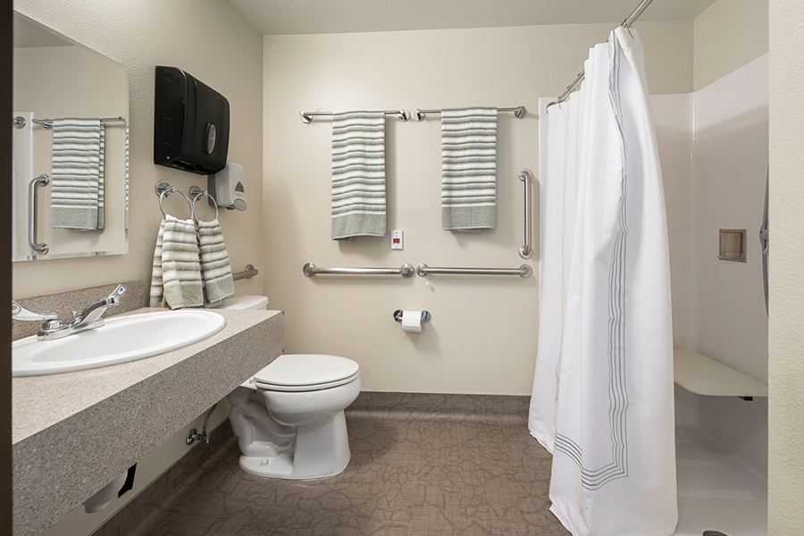 Clean, modern bathroom with towels, shower, and safety features.