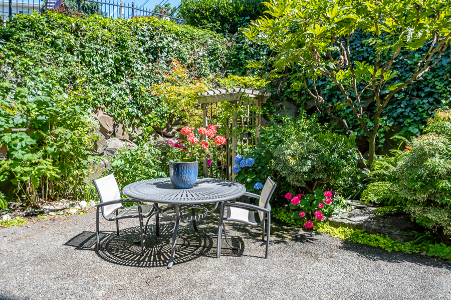 Lush garden with a table, chairs, and colorful flowers.