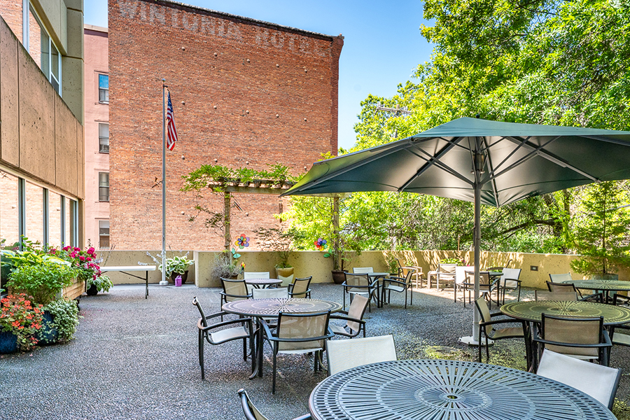 Outdoor seating area with tables, plants, and a flag.