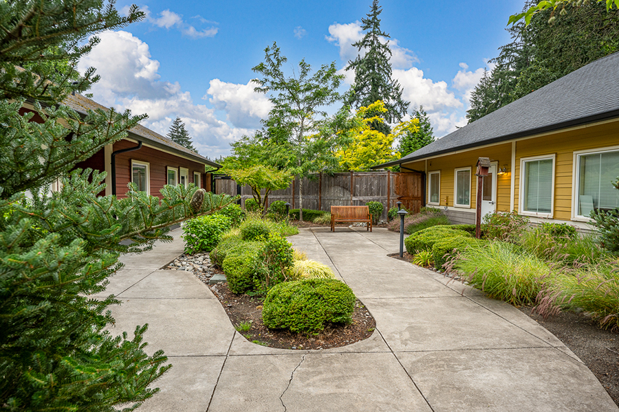 landscaped courtyard with benches and cloudy blue sky.