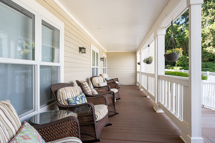 Cozy porch with wicker chairs and hanging plants.