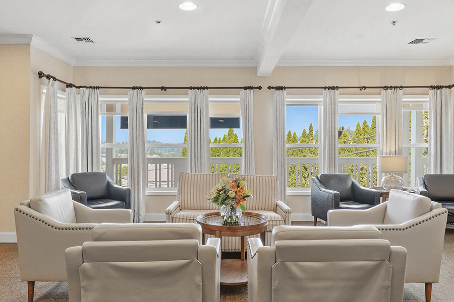 Cozy lounge with seating and large windows, bright atmosphere.