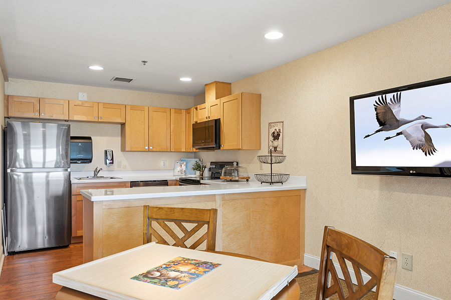 Modern kitchen with wood cabinets and TV displaying birds.