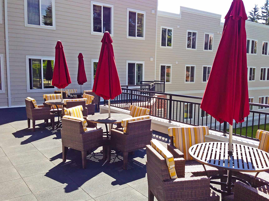 Outdoor seating area with red umbrellas and brown chairs.