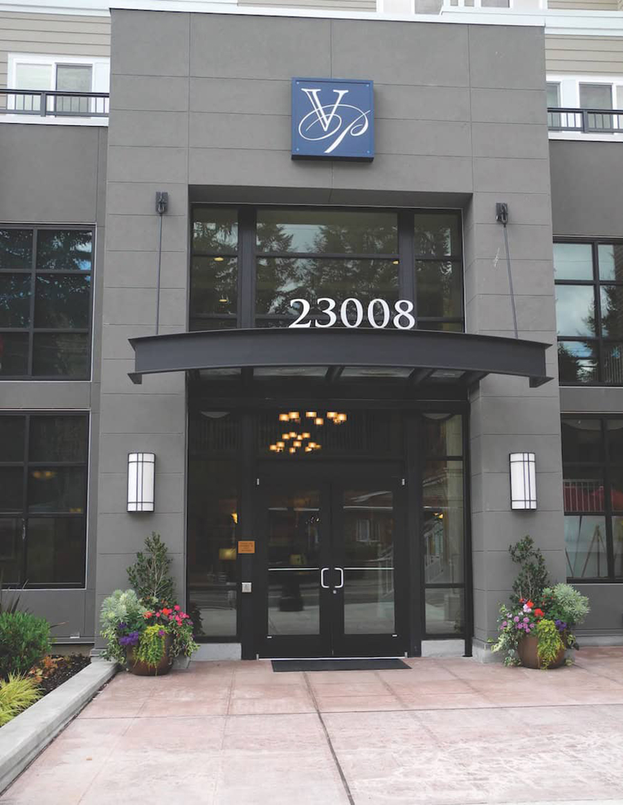 Modern building entrance with decorative plants and signage.