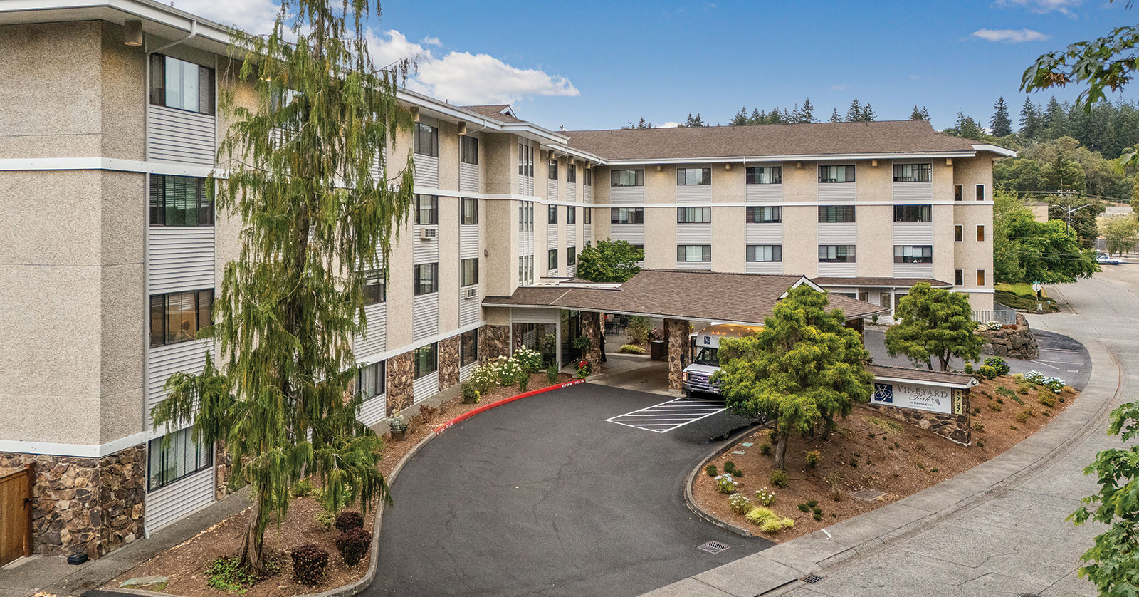 Four-story hotel with landscaped entrance and parking area.