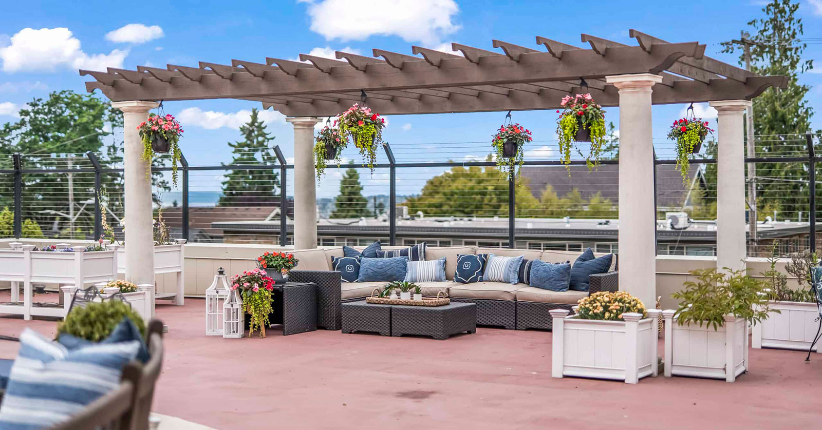 Rooftop seating area with pergola and colorful plants.