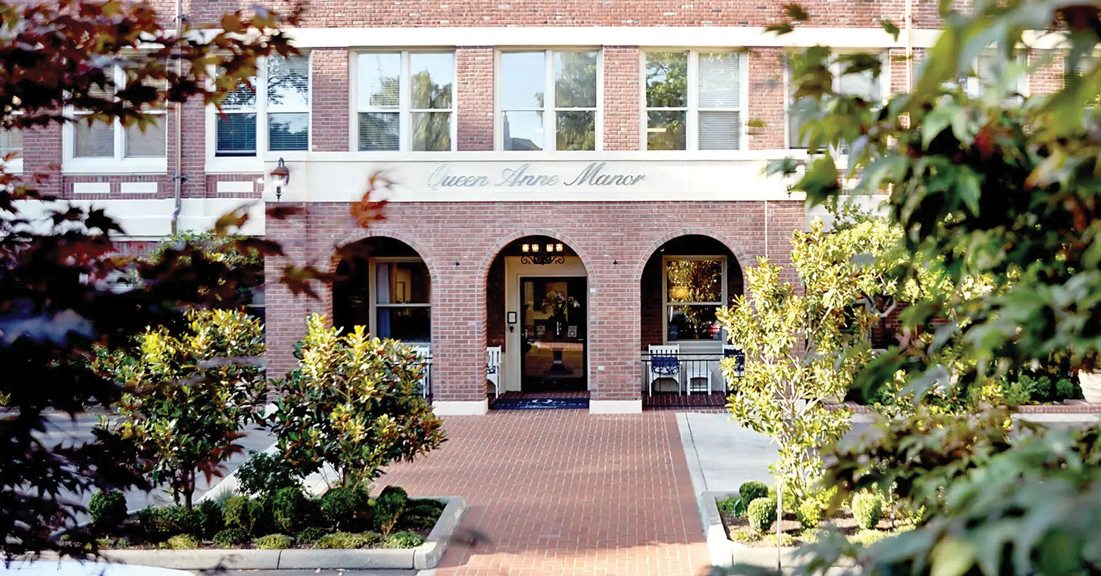 Charming brick building with arches and lush greenery.