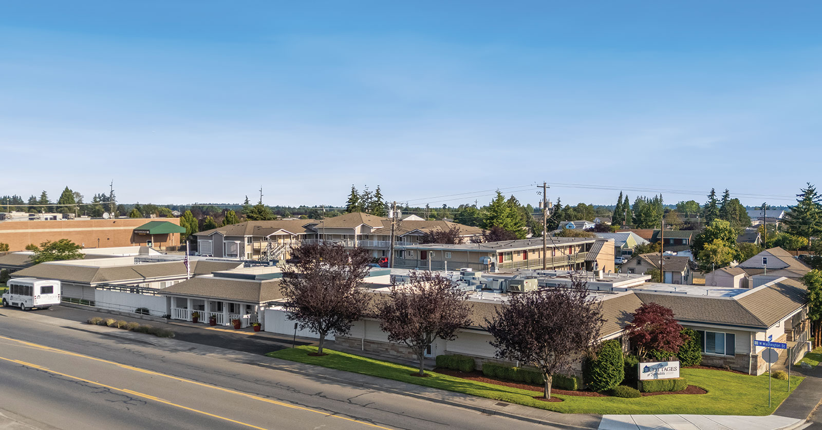 Buildings and trees along a quiet street, clear sky.