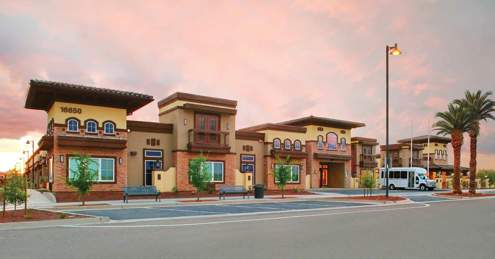 Modern building with palms, sunset sky in background.