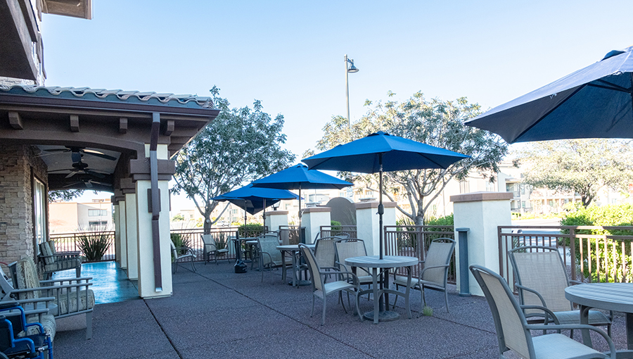 Patio area with tables and umbrellas under clear blue sky.